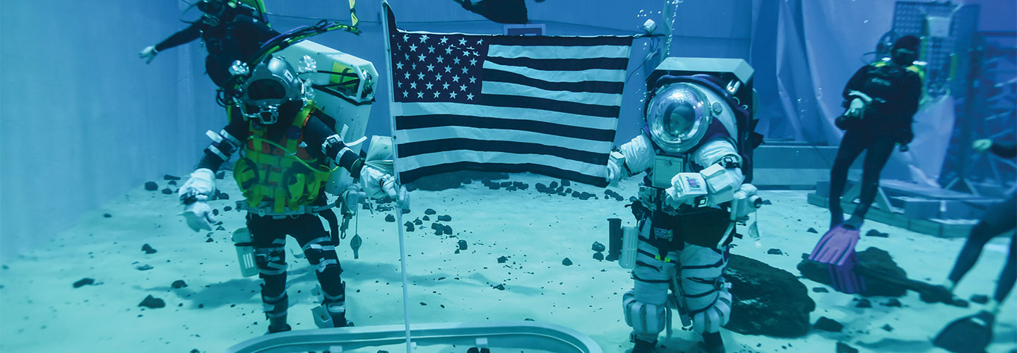 Image of people underwater wearing astronaut diving suits