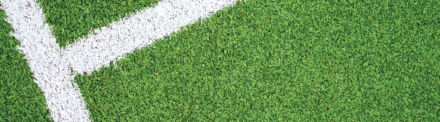A close-up view of a green sports field with white boundary lines meeting at a corner